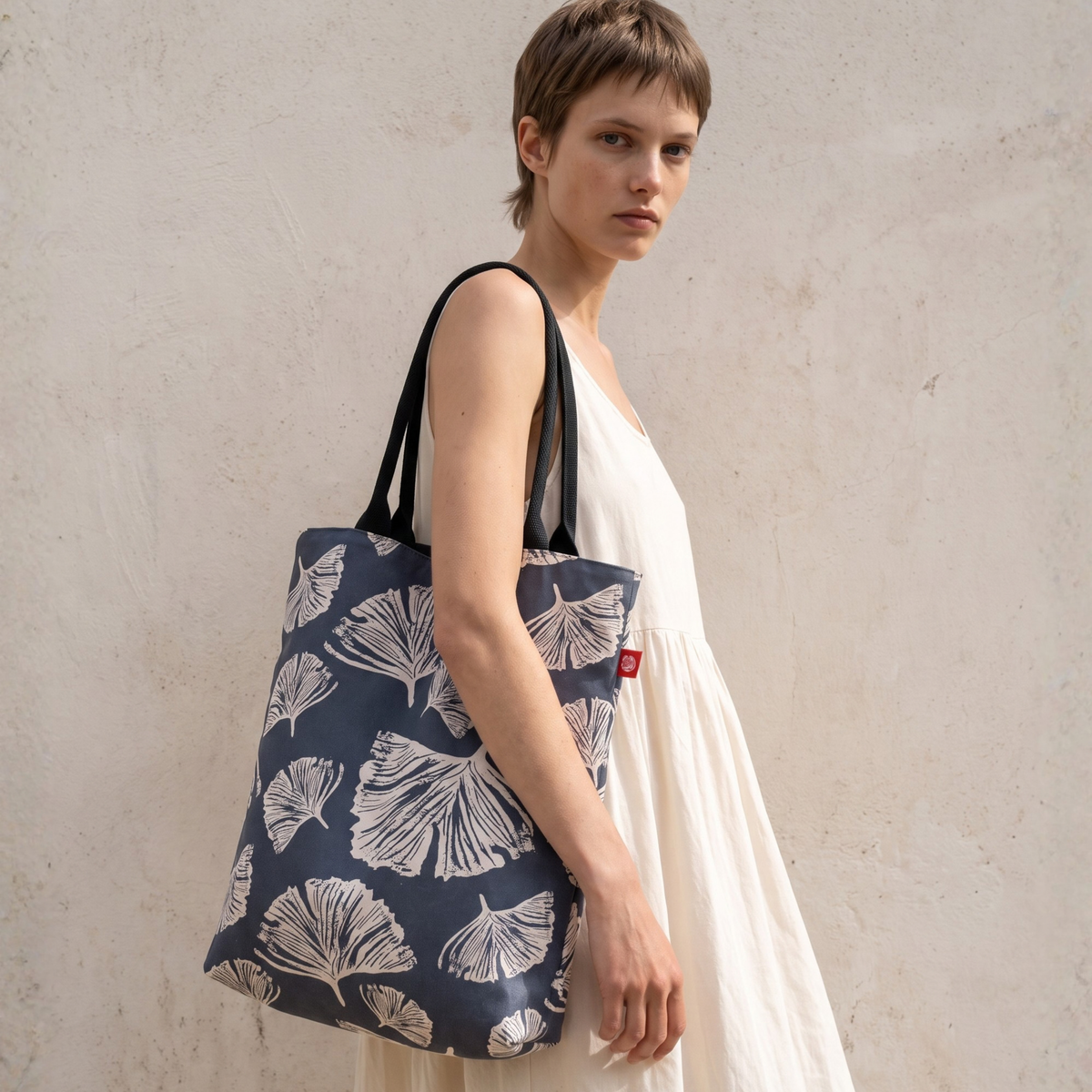 Gaia Shoulder Carry Tote in Ginkgo Poppy, model in ivory dress carrying tote on shoulder
